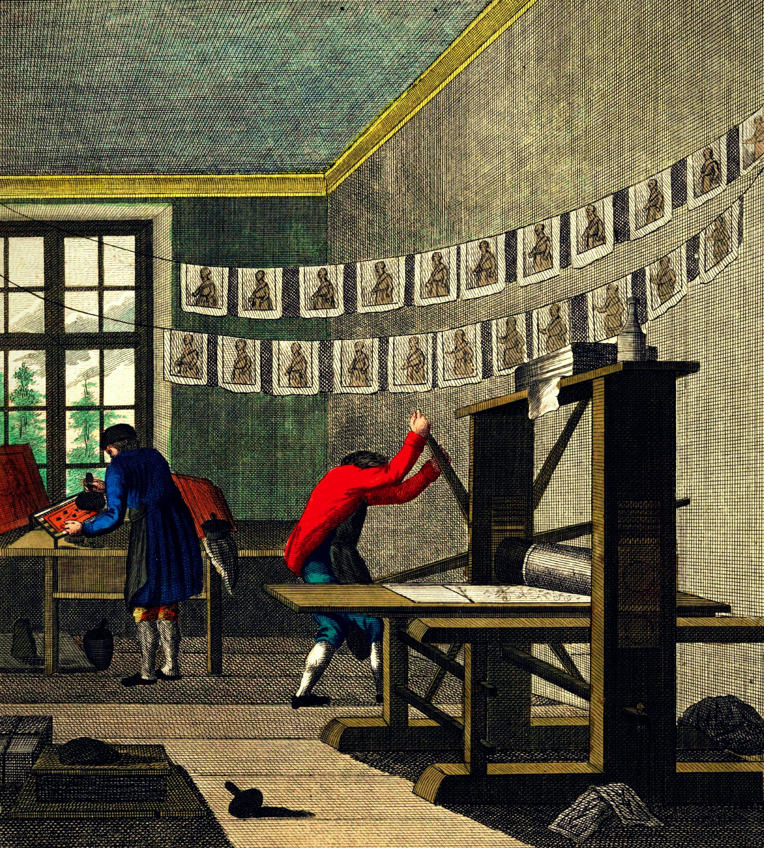 Historical engraving depicting a print shop in the 18th century. Two workers in period clothing operate a wooden printing press: one figure in a red coat pulls the press lever while bent over the press bed, and another in a blue coat inks type at a compositing table near a multi-paned window. Freshly printed sheets, each bearing a small portrait, hang in two rows on drying lines strung across the room. Ink balls, tools, and other workshop materials are scattered on the floor.