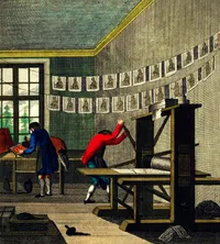Historical engraving depicting a print shop in the 18th century. Two workers in period clothing operate a wooden printing press: one figure in a red coat pulls the press lever while bent over the press bed, and another in a blue coat inks type at a compositing table near a multi-paned window. Freshly printed sheets, each bearing a small portrait, hang in two rows on drying lines strung across the room. Ink balls, tools, and other workshop materials are scattered on the floor.