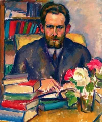 Post-impressionist oil painting of a bearded man in a dark suit and tie, seated at a desk with his forearms resting on an open book. Behind him, a bookshelf holds rows of colorful volumes, and a chair with a yellow patterned back is visible. In the foreground, stacked books in red, green, and blue bindings sit beside a glass of white and pink roses. Loose, visible brushstrokes in warm gold, blue, and coral tones.